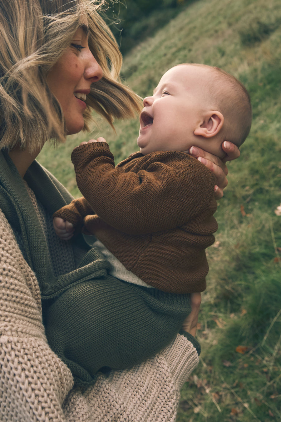 Woman holding a baby in a field
